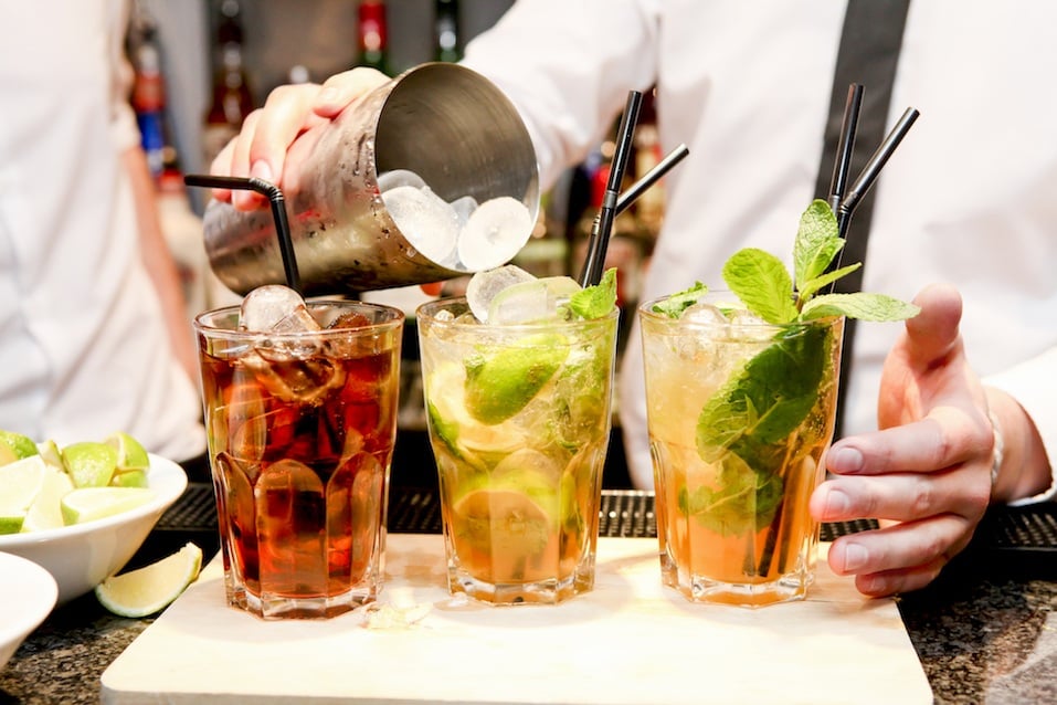 somebody making three cocktails on a bar