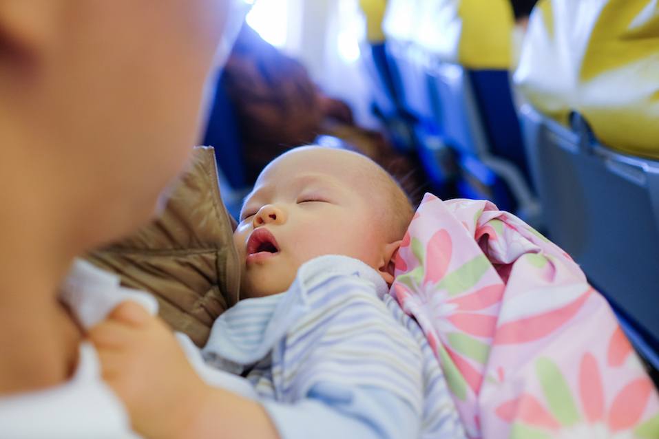 Toddler boy sleeping on father's laps while traveling in airplane