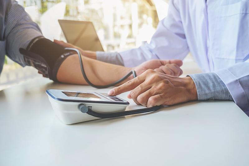 Doctor checking a young man's blood pressure