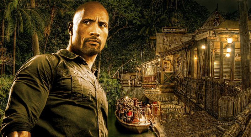 Dwayne Johnson stands with trees, a boat and house in the background