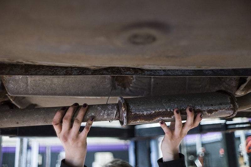 A woman mechanic fixes a car exhaust pipe as she works in an innovative garage and auto repair workshop catering exclusively to female customers, in Saint-Ouen-l'Aumone, in the suburbs of Paris, on May 14, 2014. Inspired by a similar business venture in the southern French city of Montpellier, the garage offers women an alternative to the often heavily male-dominated and macho environment of most auto repair shops, proposing them hands-on, informative classes on mechanics, and even a massage or a manicure during their waiting time.