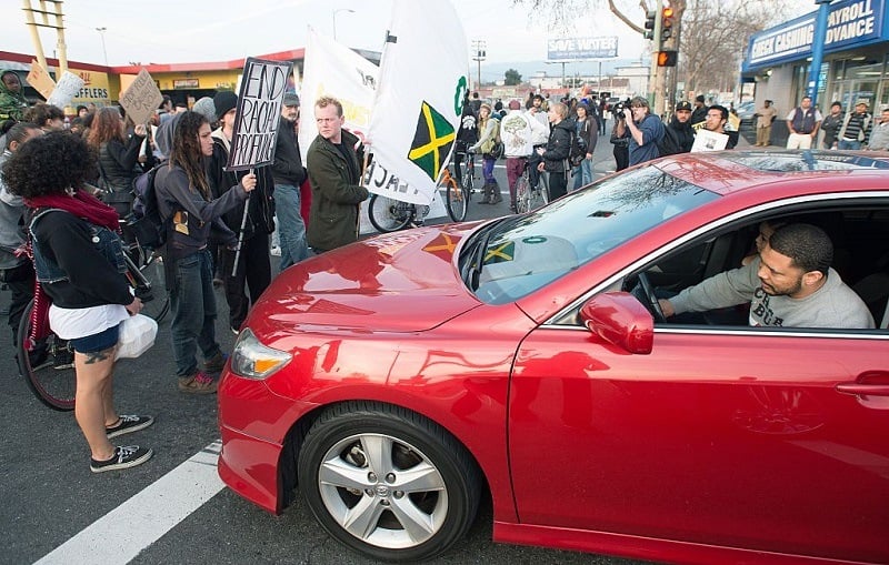 Protesters block traffic as an angry driver honks during an anti-police brutality march in Oakland on January 17, 2015. About hundred protesters disrupted traffic and chanted as they made their way to Oakland Police Station where at least five people were arrested.