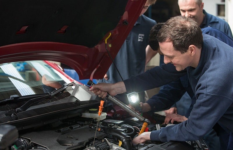 ST AUSTELL, ENGLAND - APRIL 09: Chancellor George Osbourne (R) works under the bonnet of a car that is being serviced in the service and repair workshops as he meets apprentices at Hawkins garage near St Austell on April 9, 2015 in Cornwall, England. Campaigning continues in what is predicted to be Britain's closest national election, which will take place on May 7.