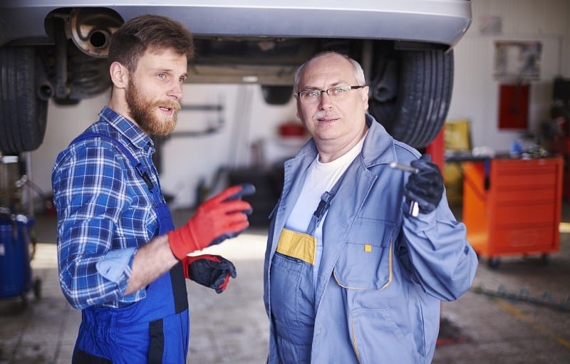 Two mechanics talking in auto repair shop