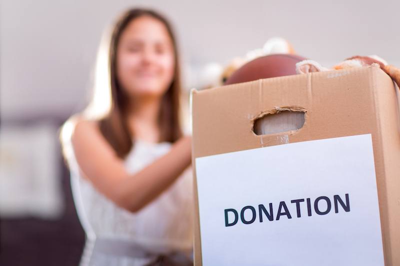 Girl taking donation box full with stuff for donate