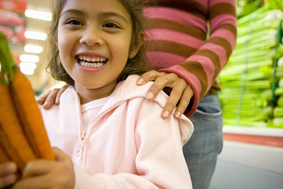 Girl holding carrots in grocery store