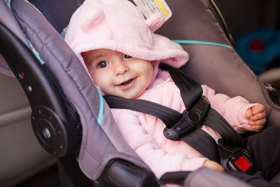 beautiful baby girl sitting on a car seat and smiling