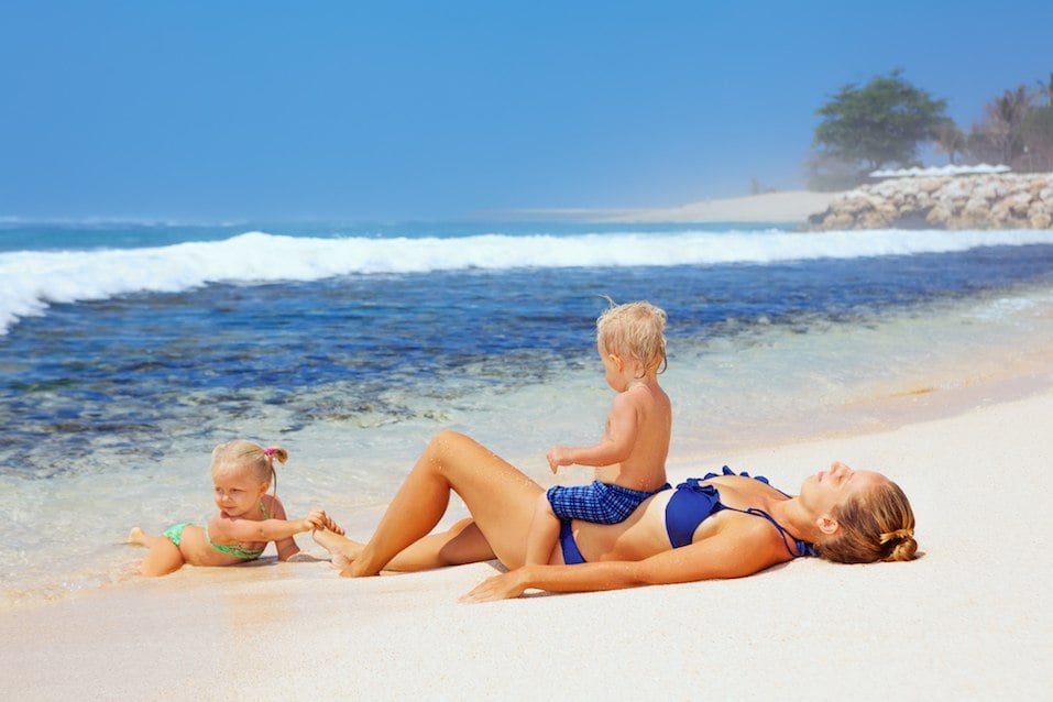 Happy family lying on sand beach and look at sea surf
