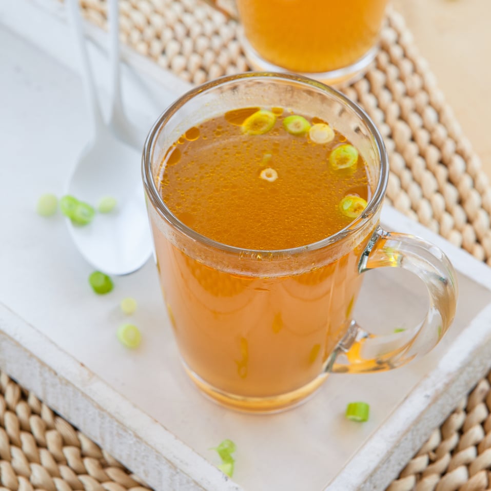 Homemade bone broth with leek in glass cup Homemade bone broth with leek in glass cup