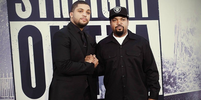 Ice Cube and O'Shea Jackson Jr. are holding hands while posing in black clothes on the red carpet.