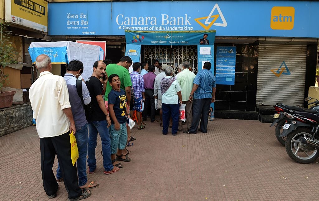 Indian customers queue outside a bank