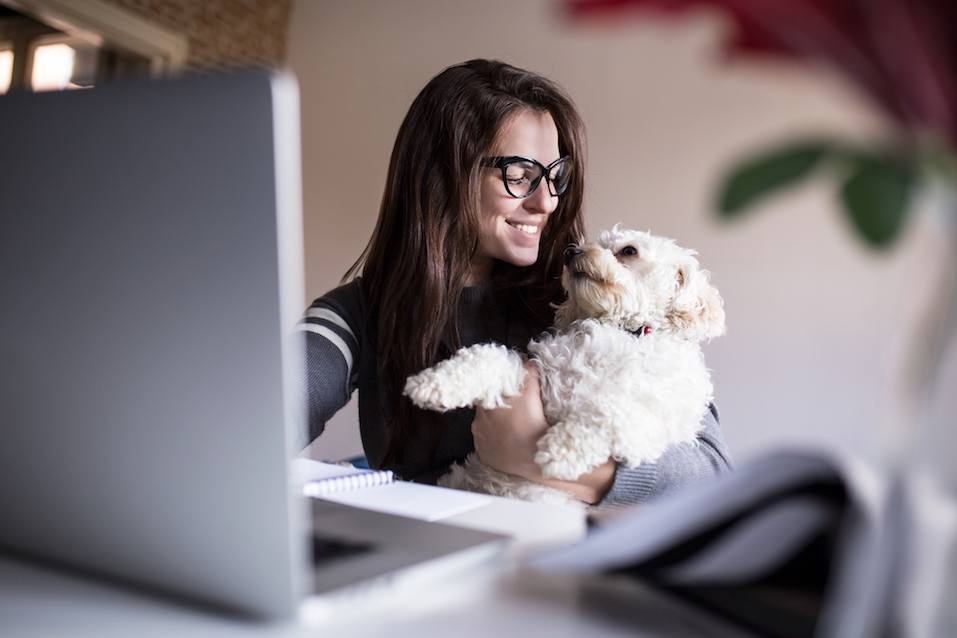 Woman and her dog at her home office hugging