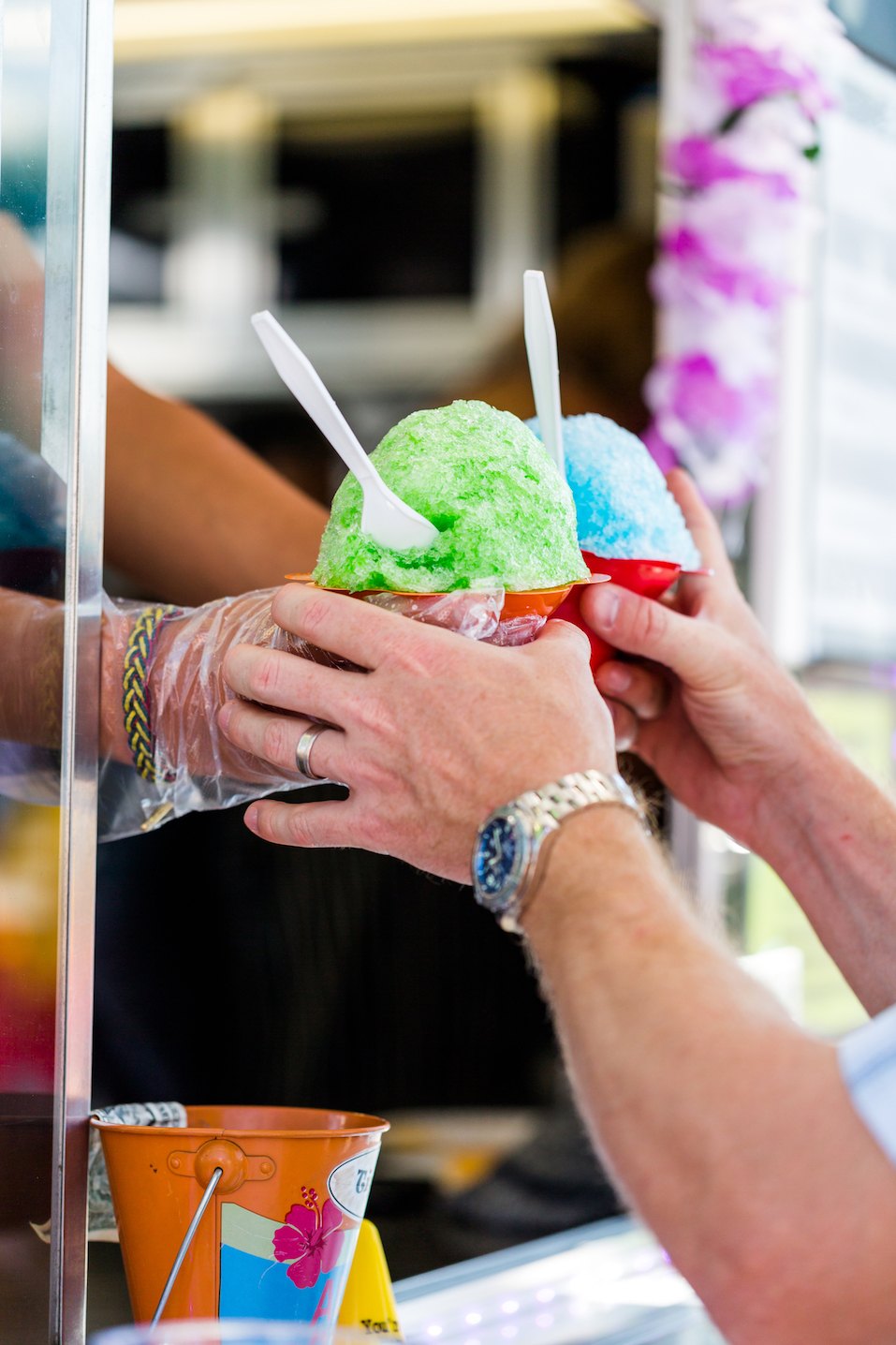 Man getting two snow cones from vendor