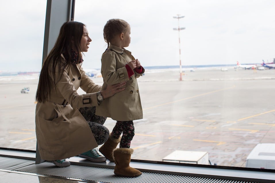 Mother and little daughter looking out the window at airport
