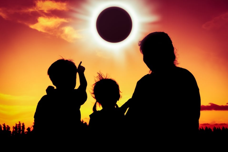 Boy point to solar eclipse on gold sky background