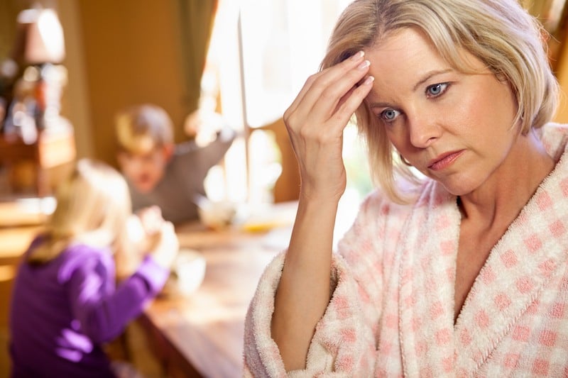 mother looking upset as her children play in the background mother looking upset as her children play in the background