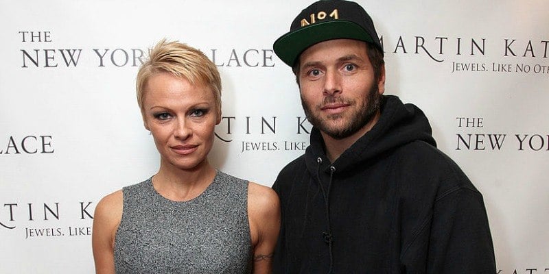 Pamela Anderson poses in a grey dress with Rick Salomon on the red carpet.