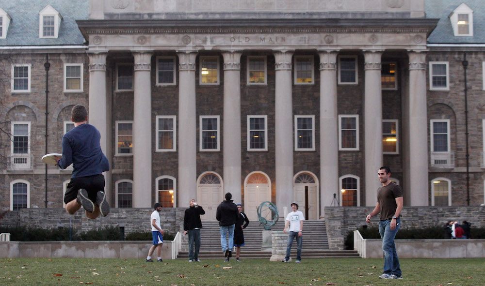 Penn State students play frisbee in front of Old Main