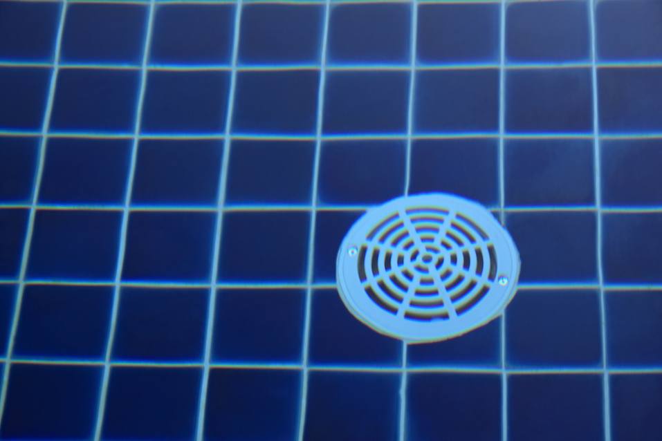 Plastic round drain hole on floor tile pool.