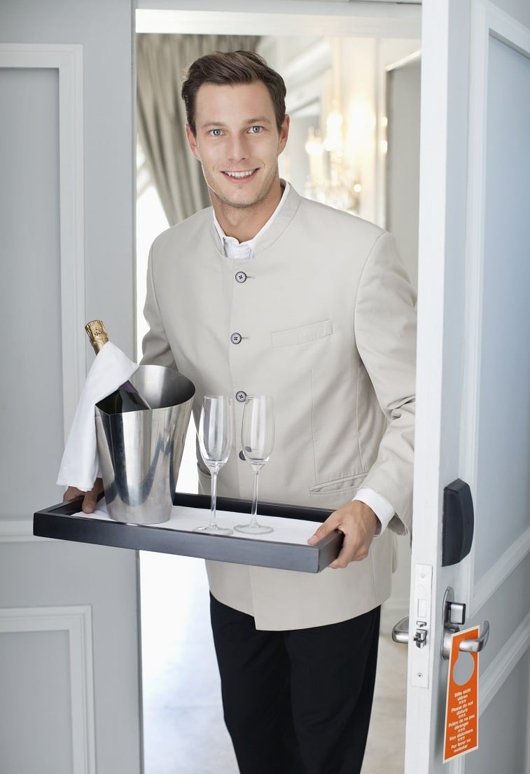 waiter in hotel room doorway with tray