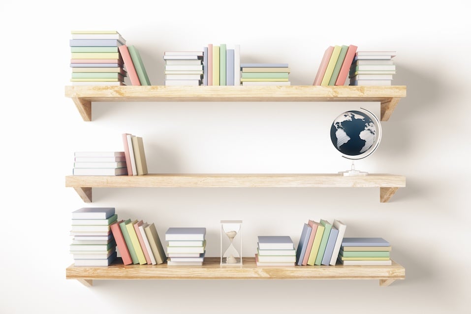 Shelves with books and other items on light wall