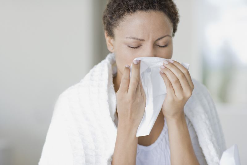 Woman blowing her nose into a tissue.