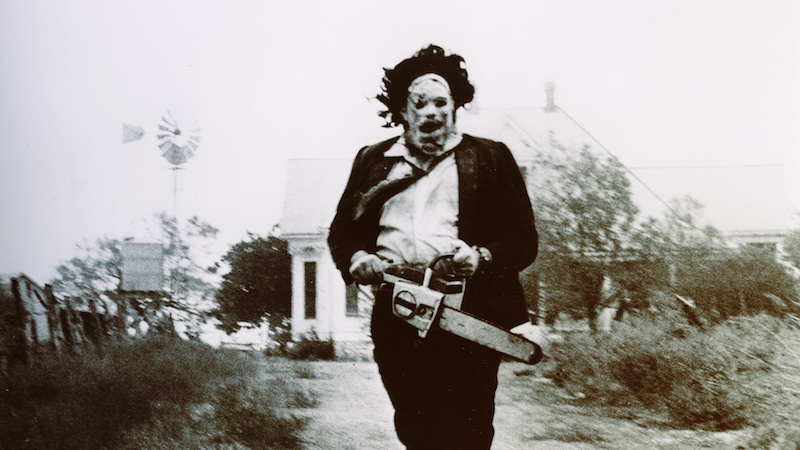 A man in a mask and suit holds a chainsaw in The Texas Chainsaw Massacre