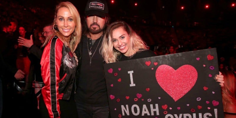 Tish, Billy Ray, and Miley Cyrus pose together as Miley holds up a poster saying "I heart Noah Cyrus." Tish, Billy Ray, and Miley Cyrus pose together as Miley holds up a poster saying "I heart Noah Cyrus."