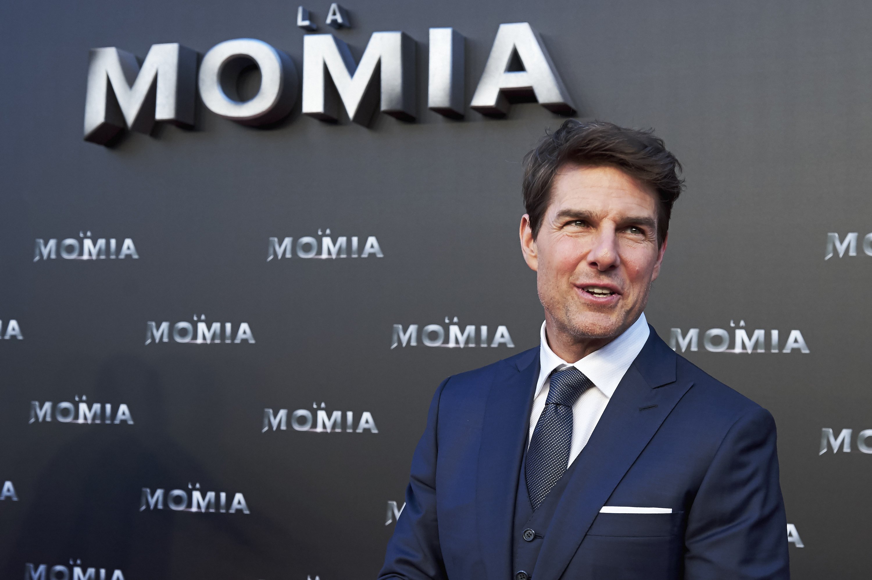 Tom Cruise smiles and looks to the side while posing for photos at a movie premiere. 