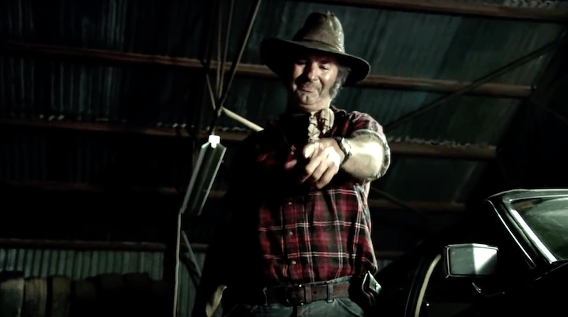 John Jarratt as Mick Taylor holding a bloody knife in Wolf Creek