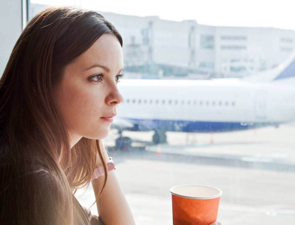 Young woman is drinking coffee in airport