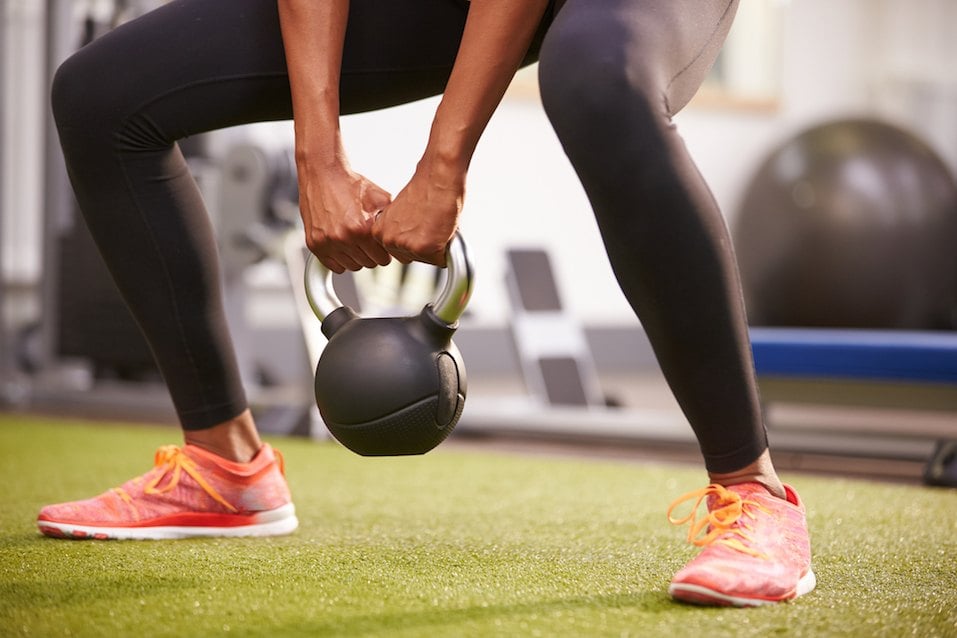 Woman exercising with a kettlebell weight, low-section crop Woman exercising with a kettlebell weight, low-section crop