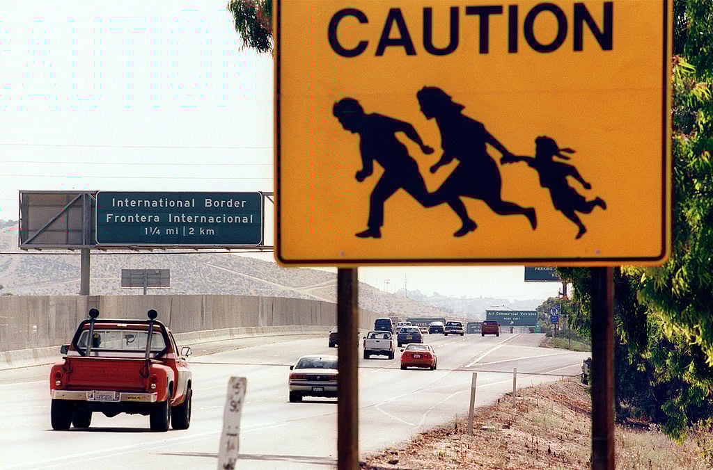 A sign warning drivers about pedestrians running across the highway