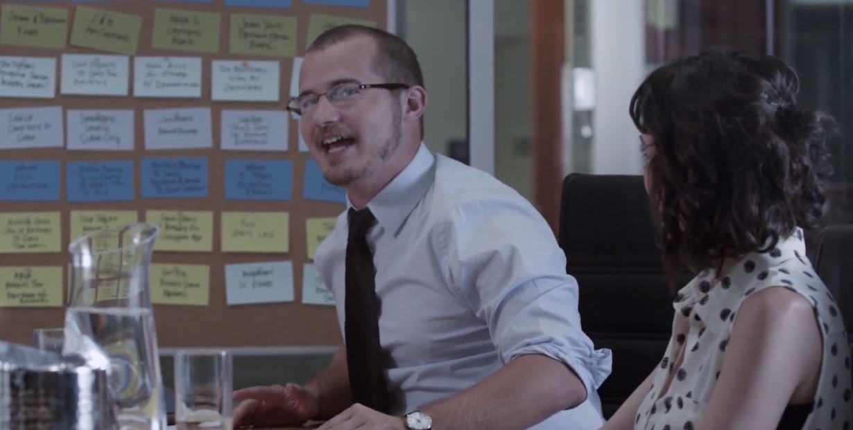 A screenshot of a man and a woman in a writer's room. A screenshot of a man and a woman in a writer's room.