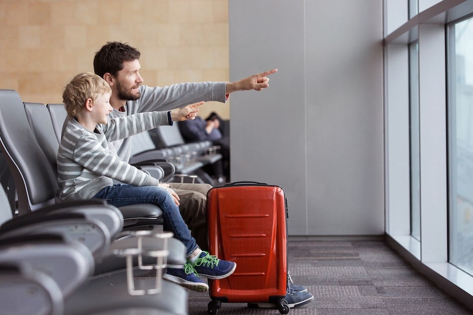 boy and his father waiting at the airport for plane departure