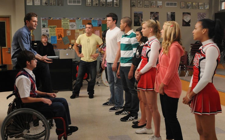 A group of students in a classroom standing next to one another across from a teacher and a boy in a wheelchair A group of students in a classroom standing next to one another across from a teacher and a boy in a wheelchair