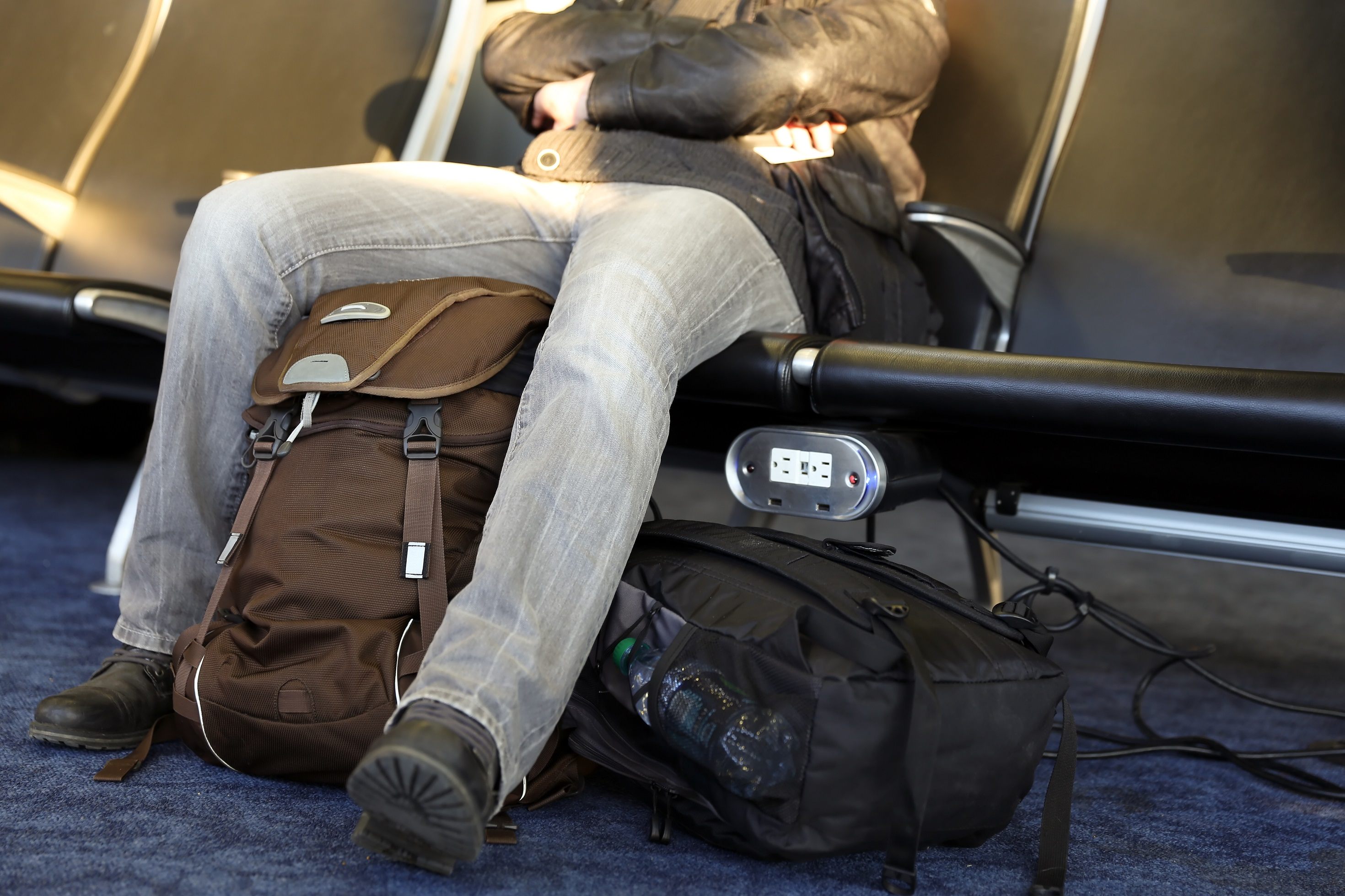 Man sitting in airport with backpacks