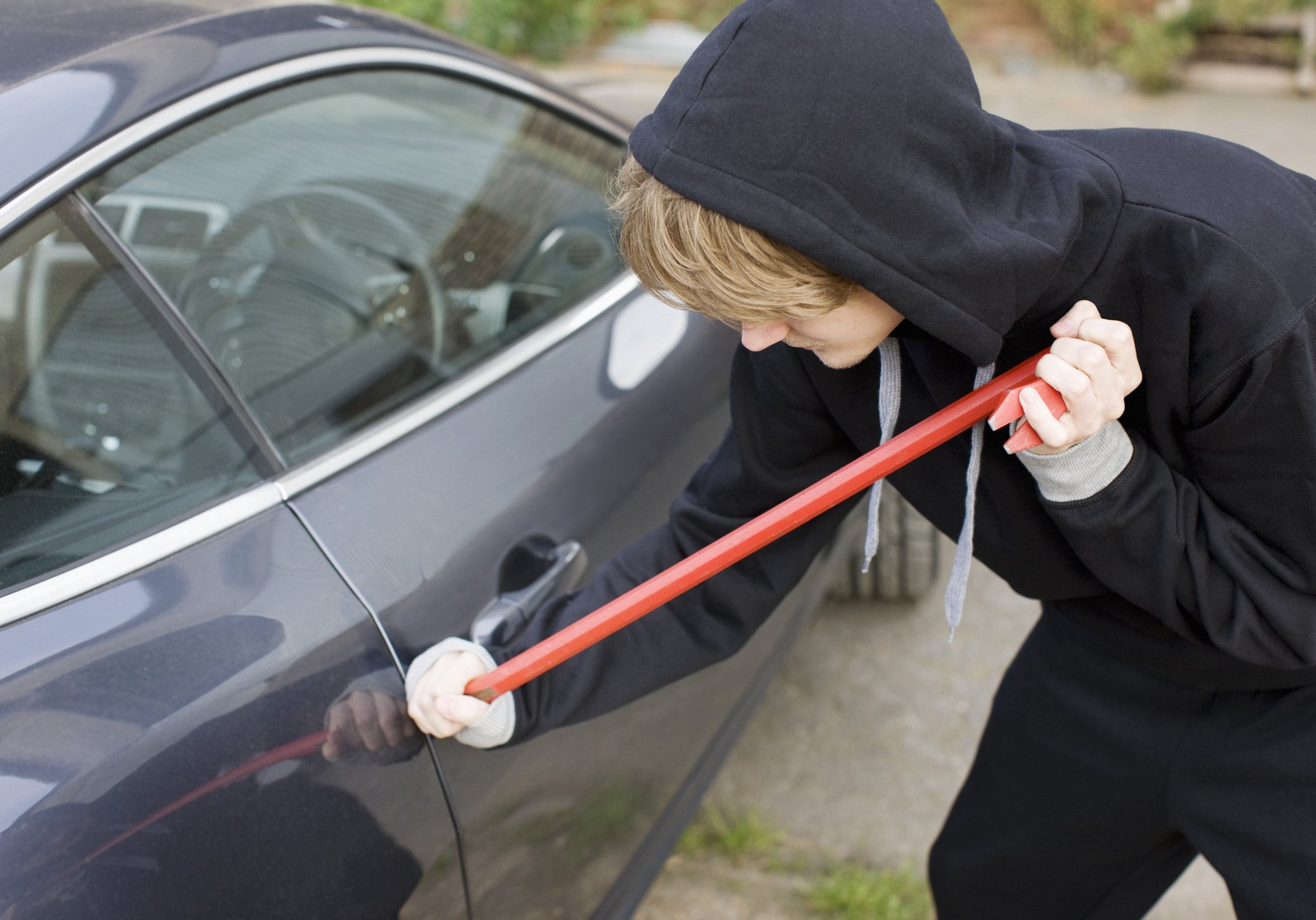 Man in hoodie breaking into car