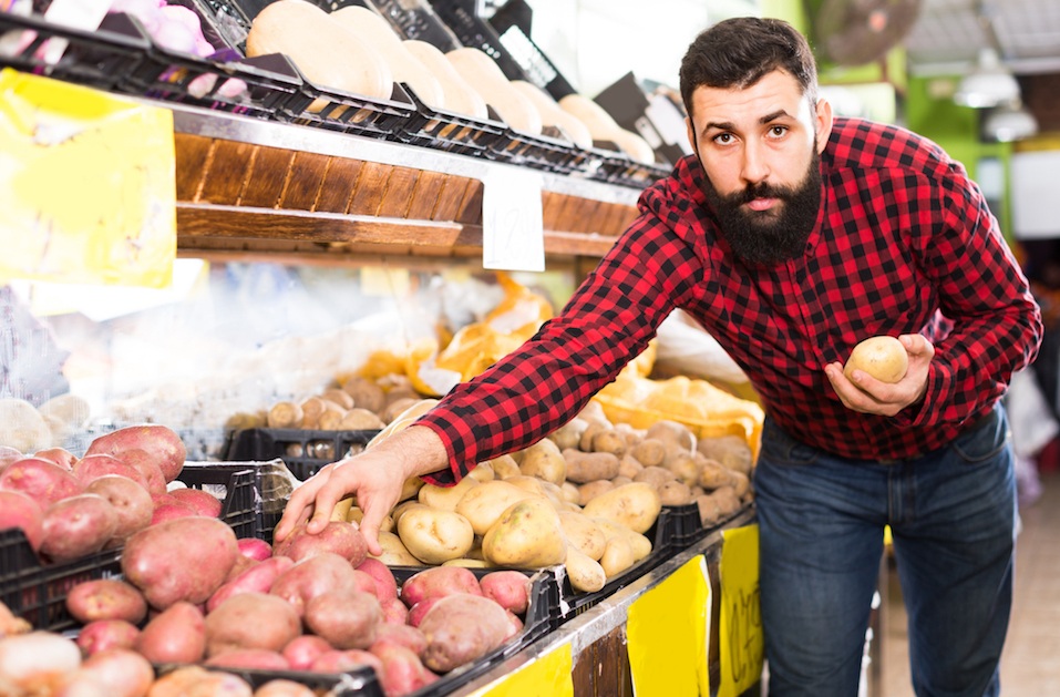 seller showing potatoes in grocery shop