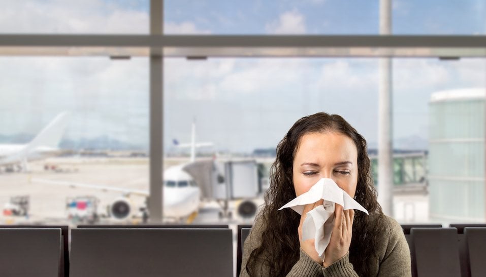 sick woman sneezing at the airport
