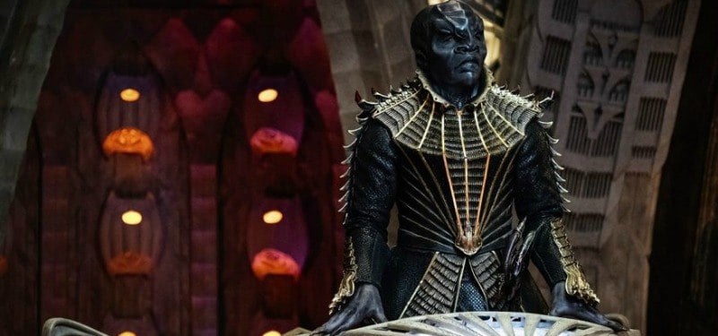 A Klingon stands behind a podium on a ship. A Klingon stands behind a podium on a ship.