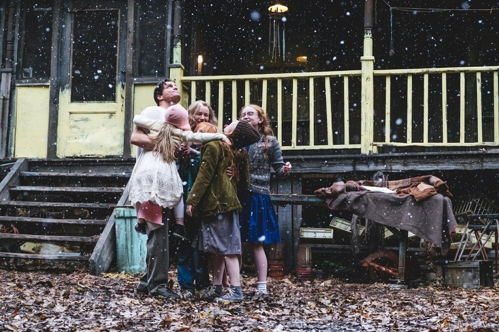 A family stands in a group embrace looking up at the falling snow A family stands in a group embrace looking up at the falling snow