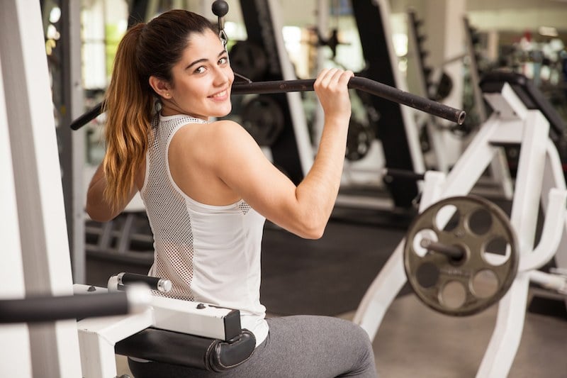 Woman using a pulldown bar machine in the gym Woman using a pulldown bar machine in the gym