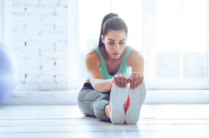 Low weights and high reps are key to building muscle. woman stretching at the gym