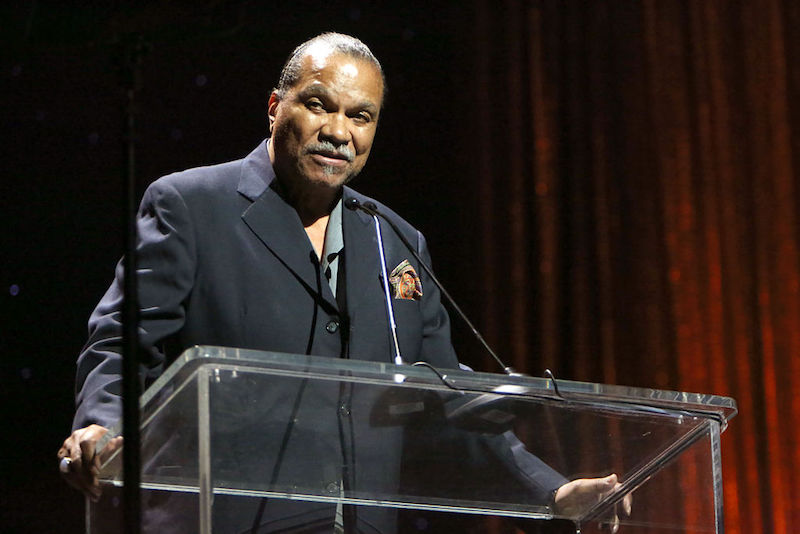 Billy Dee Williams stands at a glass podium during an awards show. Billy Dee Williams stands at a glass podium during an awards show.