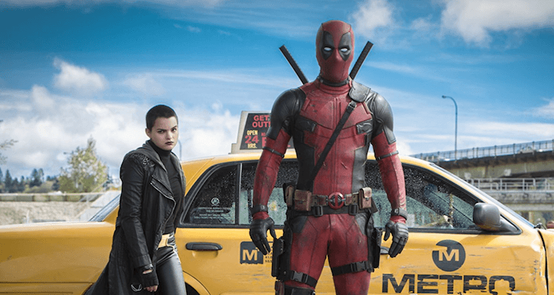 Deadpool stands in front of a yellow taxi.