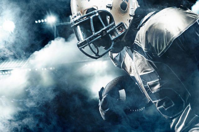 A football player stands in front of a field and smoke. A football player stands in front of a field and smoke.