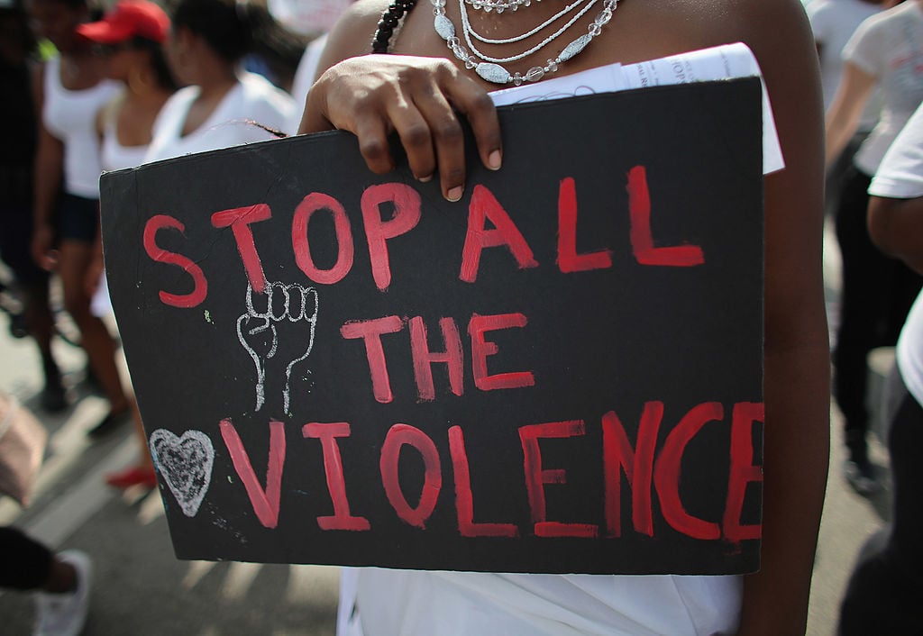 A college student holds a sign readingn " Stop All The Violence as she participates in the College Bride's Walk from Barry University in Miami Shores, Florida.
