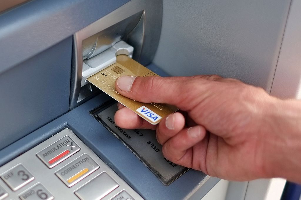 A man takes out banknotes from an automated teller machine (ATM)