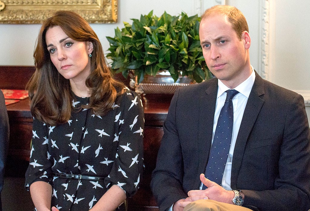 Kate Middleton and Prince William sit together as they listen intently at someone's conversation.